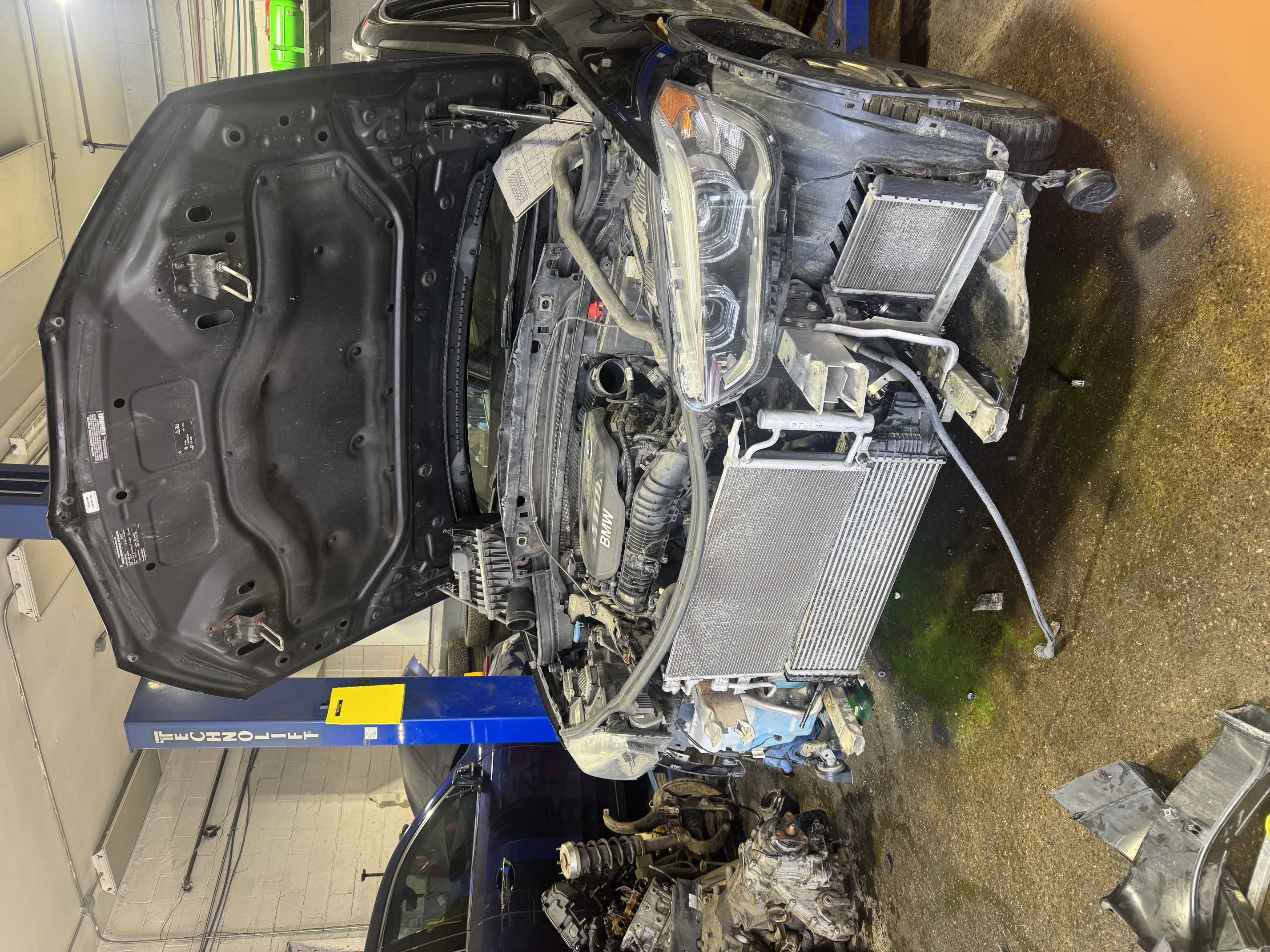 A BMW with its hood open during engine repairs in the workshop